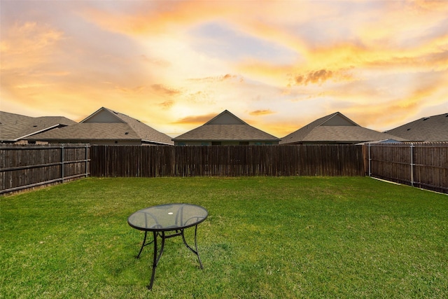yard at dusk featuring a fenced backyard