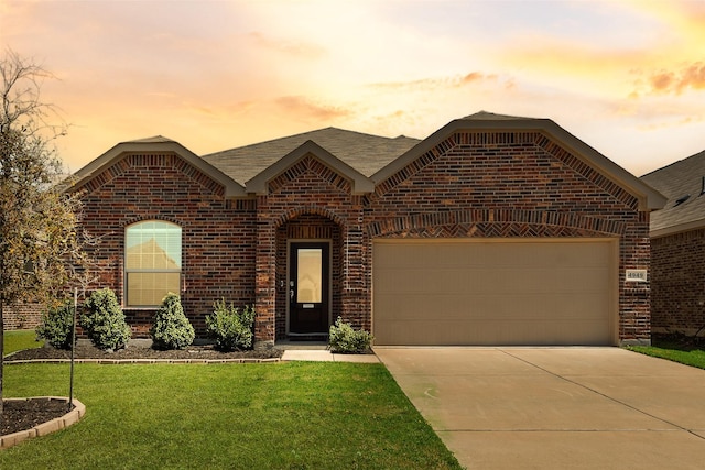 view of front facade featuring roof with shingles, driveway, a front yard, brick siding, and a garage