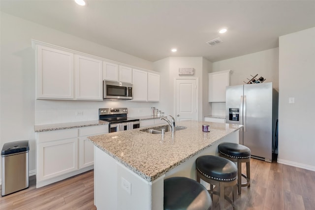 kitchen featuring a sink, stainless steel appliances, light wood finished floors, and visible vents