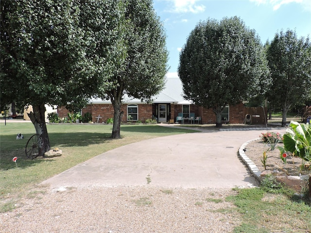 ranch-style house featuring brick siding, curved driveway, and a front yard