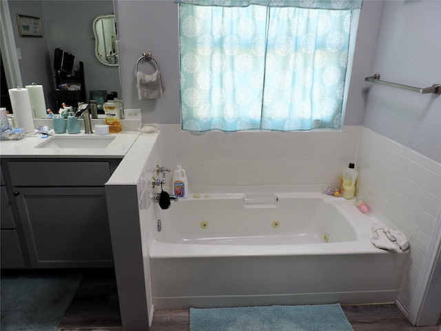 full bath with a whirlpool tub, wood finished floors, and vanity