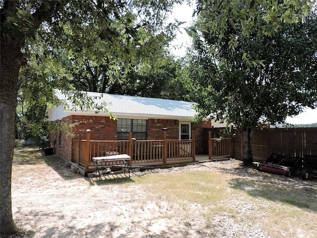 rear view of house with brick siding, fence, and a deck
