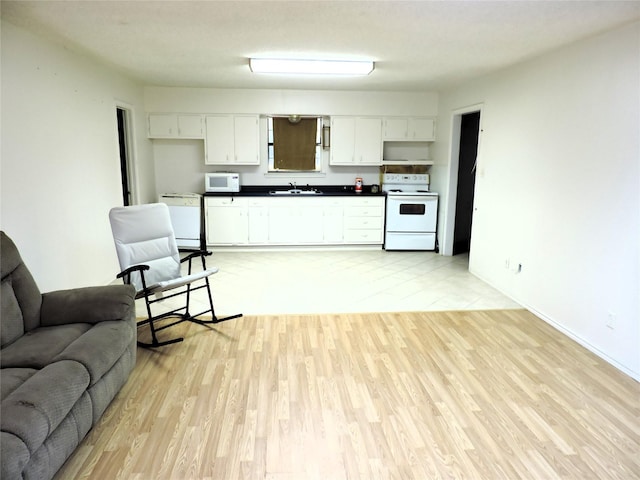 kitchen featuring a sink, open floor plan, white appliances, dark countertops, and light wood-style floors