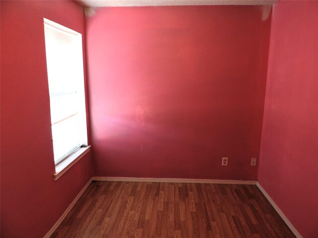 empty room featuring dark wood finished floors and baseboards