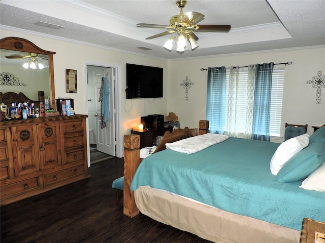 bedroom featuring a tray ceiling, dark wood finished floors, ornamental molding, and a textured ceiling