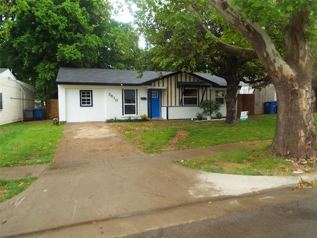 ranch-style house with fence, concrete driveway, a front lawn, stucco siding, and a shingled roof