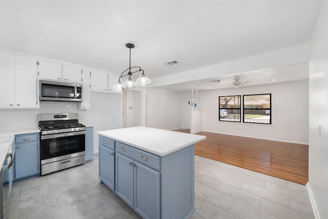 kitchen with light countertops, backsplash, blue cabinets, stainless steel appliances, and white cabinets
