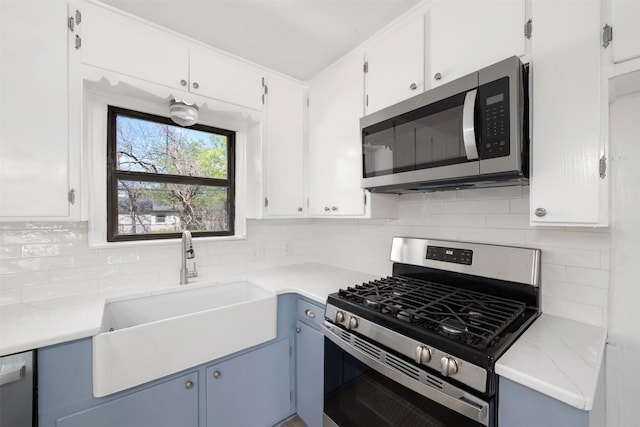 kitchen with backsplash, white cabinets, a sink, and stainless steel appliances
