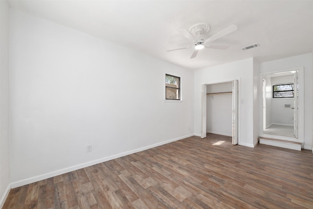 unfurnished bedroom featuring multiple windows, visible vents, wood finished floors, and baseboards