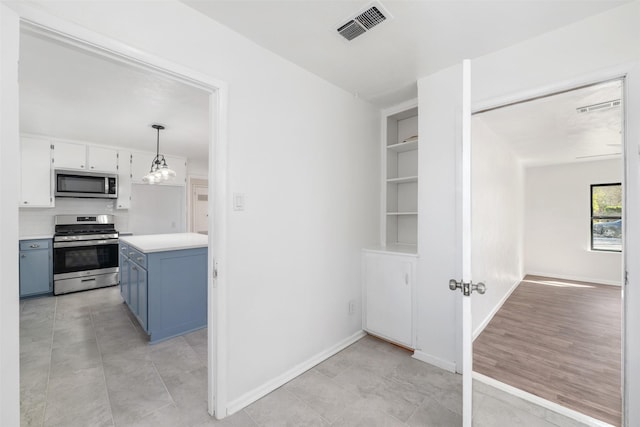 kitchen with white cabinetry, light countertops, blue cabinetry, stainless steel appliances, and visible vents