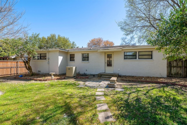 back of house with cooling unit, fence, entry steps, brick siding, and a lawn