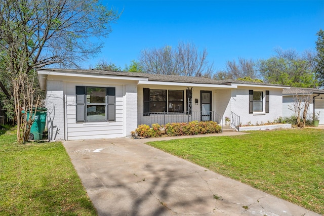 ranch-style house featuring covered porch, brick siding, a front yard, and concrete driveway