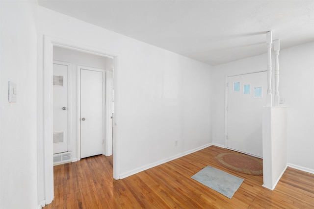 spare room featuring baseboards, visible vents, and wood finished floors