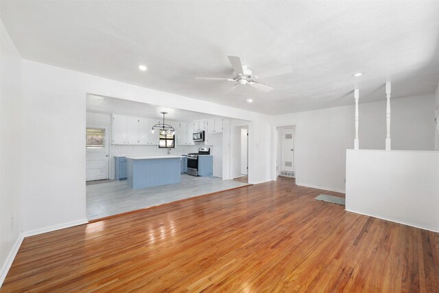 unfurnished living room with baseboards, ceiling fan, recessed lighting, and light wood finished floors