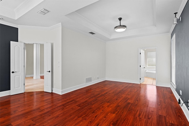 spare room featuring a tray ceiling, visible vents, and wood finished floors