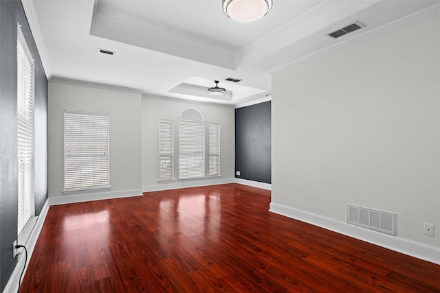 empty room with visible vents, wood finished floors, and a raised ceiling