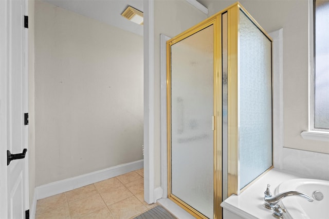 bathroom featuring tile patterned floors, a bath, baseboards, and a shower stall