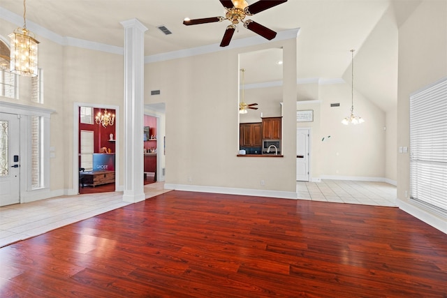 unfurnished living room featuring ornamental molding, ceiling fan with notable chandelier, baseboards, a high ceiling, and light wood-style floors