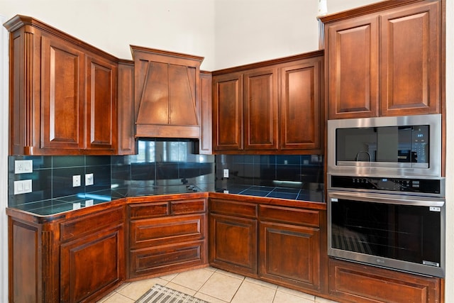 kitchen featuring backsplash, stainless steel appliances, tile counters, and light tile patterned floors