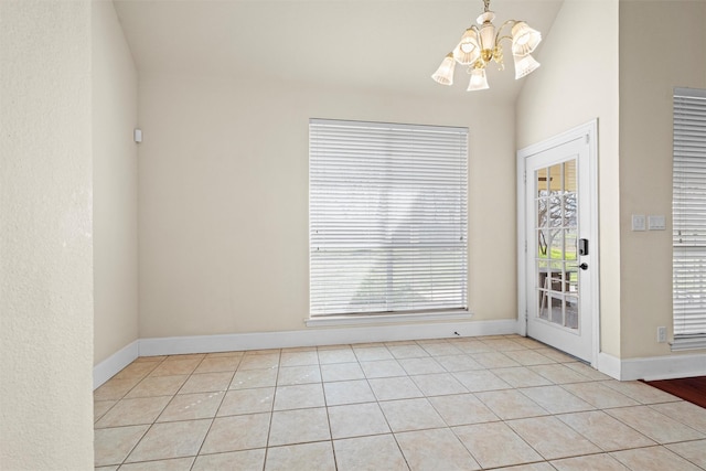 unfurnished room featuring baseboards, lofted ceiling, light tile patterned floors, and a chandelier