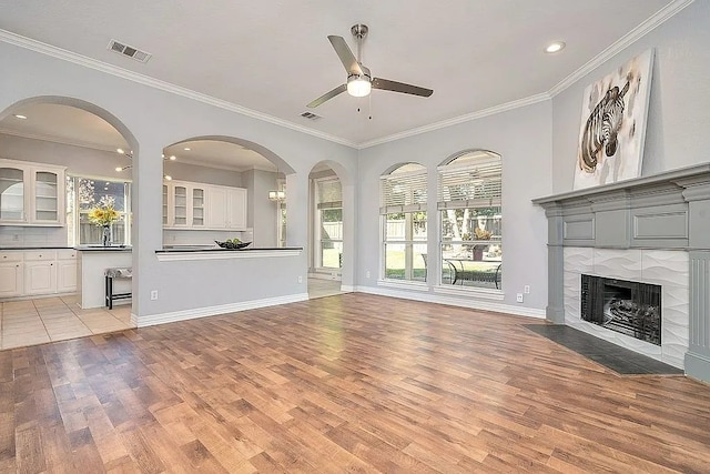 4726 Steeple Chase Ln, Rockwall, TX 75032 - unfurnished living room with light wood-style flooring, ceiling fan, crown molding, a tiled fireplace, and recessed lighting