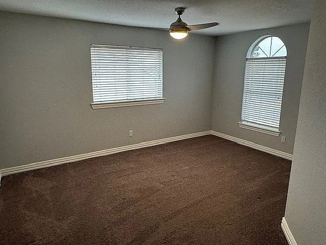 4726 Steeple Chase Ln, Rockwall, TX 75032 - empty room with a ceiling fan and dark carpet