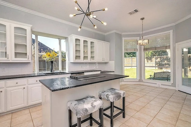 4726 Steeple Chase Ln, Rockwall, TX 75032 - kitchen with a chandelier, light tile patterned floors, dark countertops, black electric cooktop, and crown molding