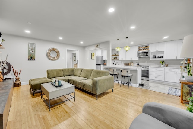 living area with baseboards, light wood-style floors, and recessed lighting
