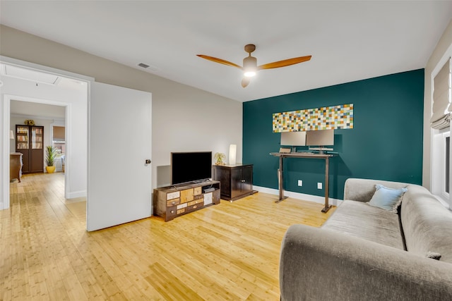 living room with a ceiling fan, hardwood / wood-style flooring, baseboards, and visible vents