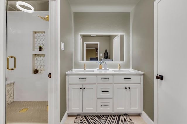 full bath featuring a shower stall, double vanity, baseboards, and a sink