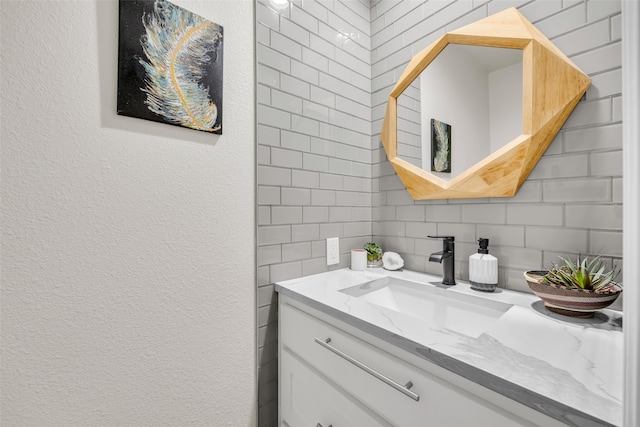 bathroom with vanity, a textured wall, and decorative backsplash