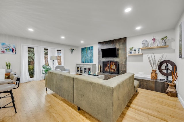 living area featuring baseboards, a tile fireplace, recessed lighting, and wood-type flooring