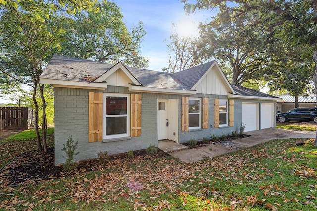 view of front of property featuring roof with shingles, brick siding, a garage, and fence