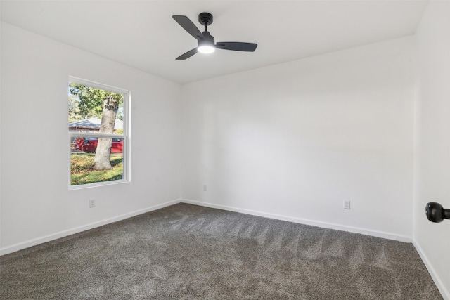 unfurnished room with baseboards, dark carpet, and a ceiling fan