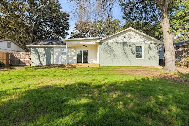 back of house featuring brick siding, fence, ceiling fan, and a yard