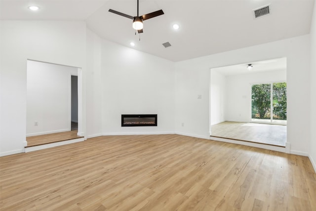 unfurnished living room featuring a glass covered fireplace, light wood-type flooring, baseboards, visible vents, and ceiling fan