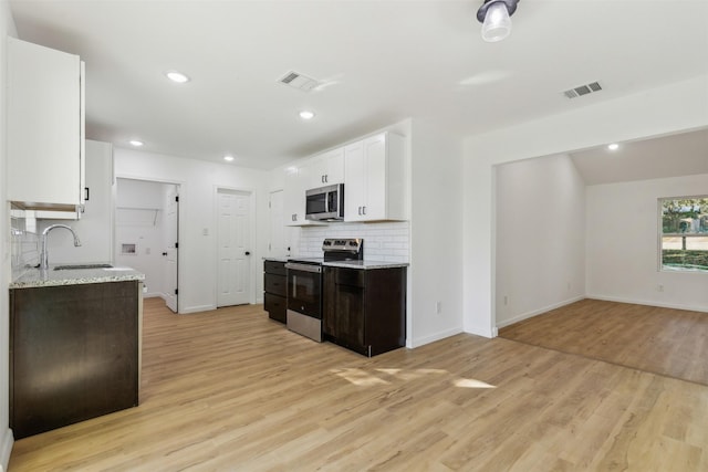 kitchen with white cabinetry, decorative backsplash, stainless steel appliances, and visible vents