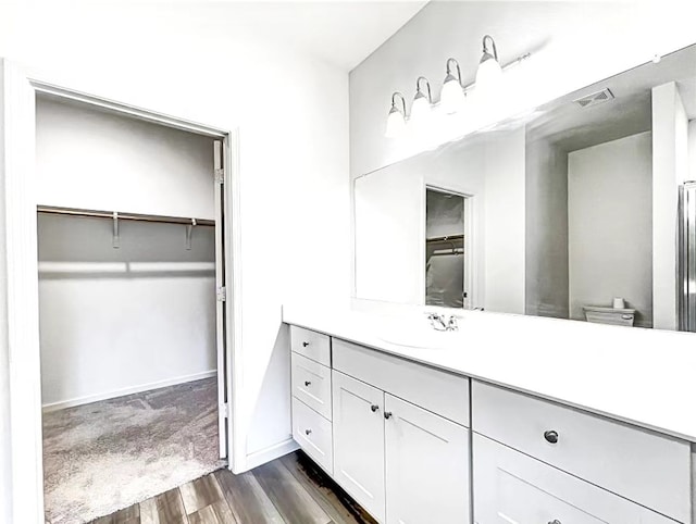1637 Escondido Dr, Fort Worth, TX 76052 - bathroom with visible vents, baseboards, wood finished floors, vanity, and a walk in closet