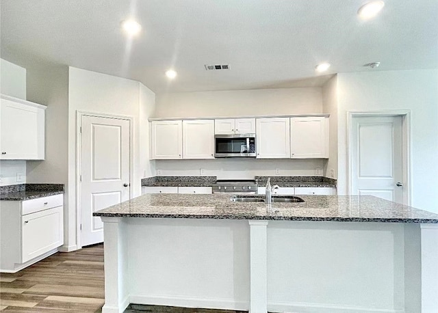 1637 Escondido Dr, Fort Worth, TX 76052 - kitchen featuring white cabinets, a center island with sink, appliances with stainless steel finishes, dark stone countertops, and a sink