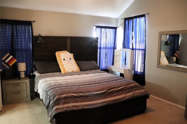 bedroom with baseboards, vaulted ceiling, and light colored carpet