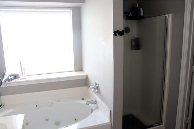 bathroom featuring a tub with jets and a stall shower