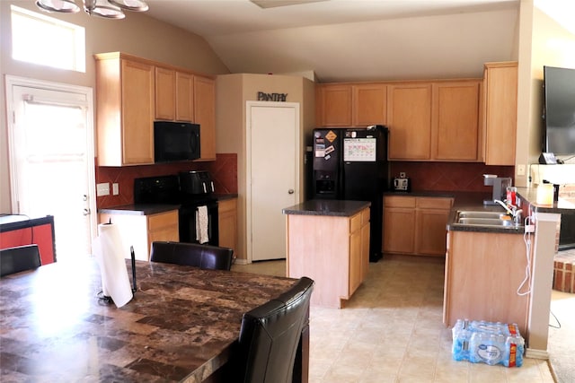 kitchen featuring a sink, a center island, lofted ceiling, dark countertops, and black appliances