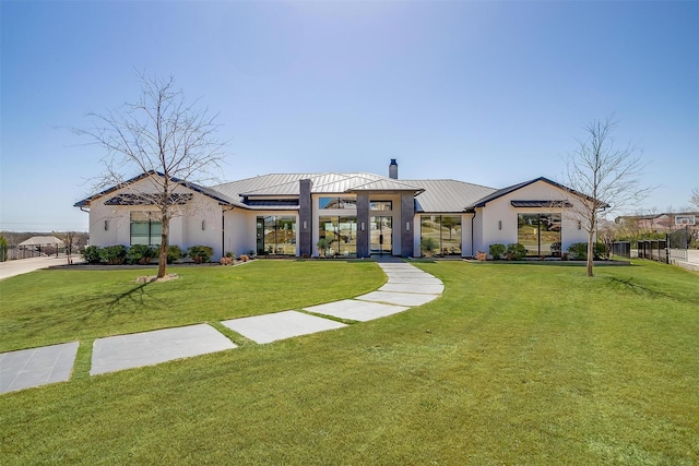 view of front of home featuring metal roof, a chimney, and a front lawn