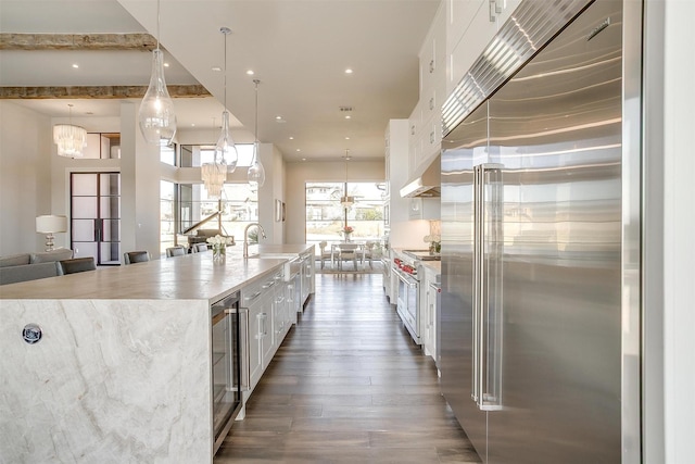 kitchen with an inviting chandelier, white cabinetry, dark wood-type flooring, wine cooler, and premium appliances