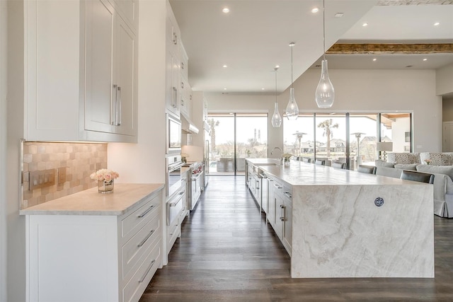 kitchen with a sink, backsplash, white cabinetry, and dark wood-type flooring