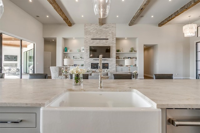 kitchen with built in features, a fireplace, light stone counters, open floor plan, and decorative light fixtures