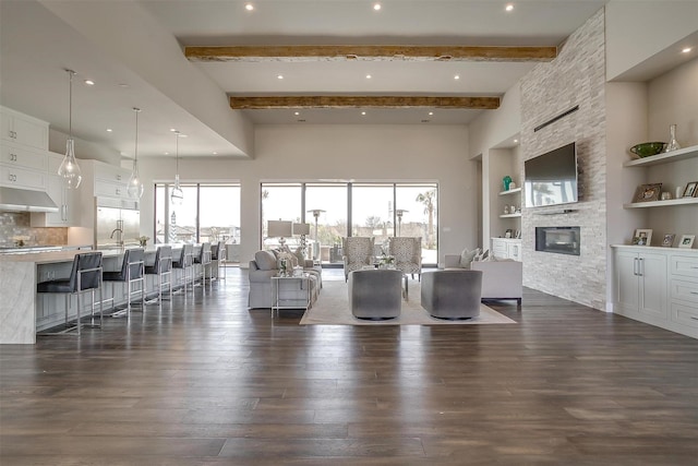 living room with dark wood-type flooring, beamed ceiling, a fireplace, and built in shelves
