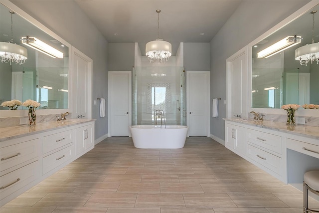 full bathroom with baseboards, tiled shower, an inviting chandelier, and vanity