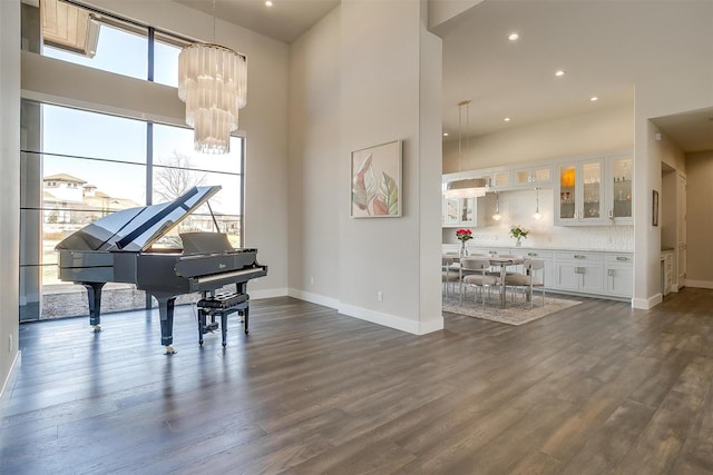 living area with a towering ceiling, baseboards, a chandelier, recessed lighting, and dark wood-type flooring