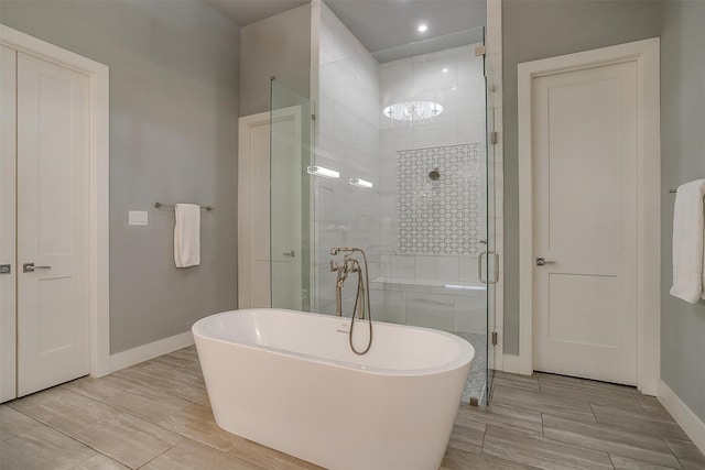full bathroom featuring a shower stall, a freestanding tub, baseboards, and wood tiled floor